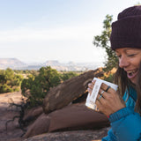 A collection of Kleen Kanteen 12oz Camping Mugs stacked on top of a rock