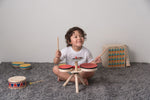 Overhead view of the Plan Toys Musical Band Children's Drum Kit being played by a toddler