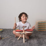 Overhead view of the Plan Toys Musical Band Children's Drum Kit being played by a toddler