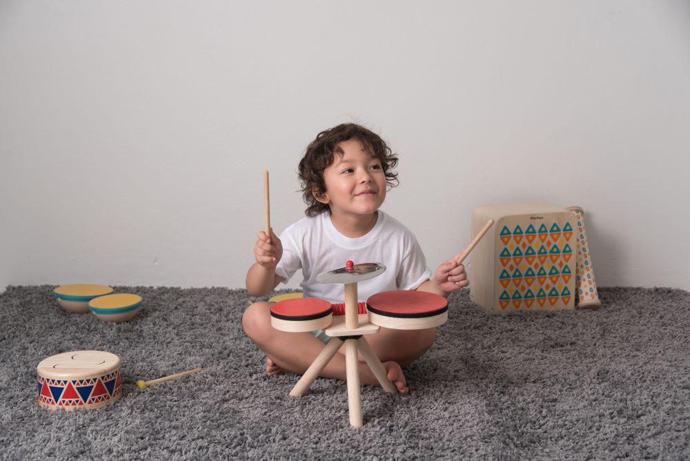 Overhead view of the Plan Toys Musical Band Children's Drum Kit being played by a toddler