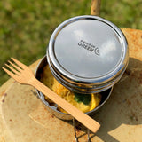 A close up of food items inside one of the tins from the stainless steel A slice of green chapra two tier round lunchbox with a bamboo fork laying on top