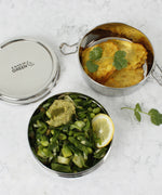 A top down image of the A slice of green chapra two tier round lunchbox  with food inside