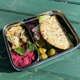 A close up of the A slice of green large lunchbox with mini container on a wooden table with various food items inside