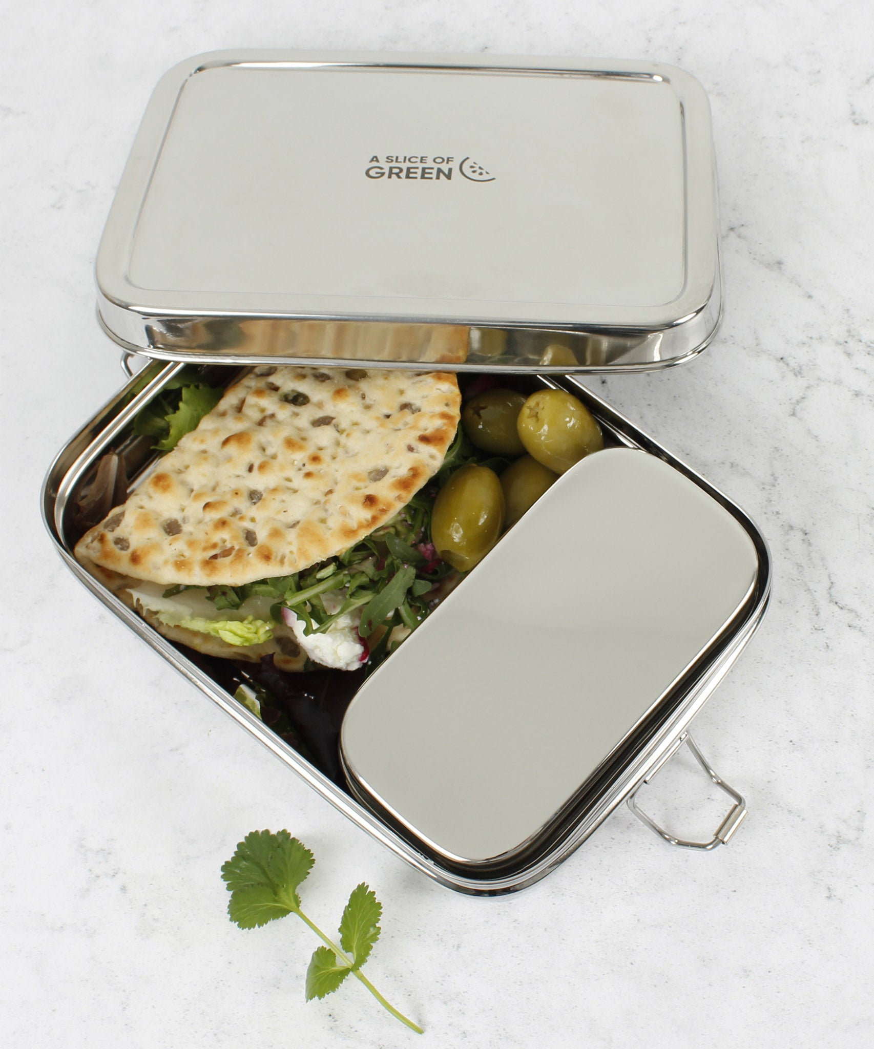 A close up of the A slice of green large lunchbox with mini container with various food items inside and the lid resting on top