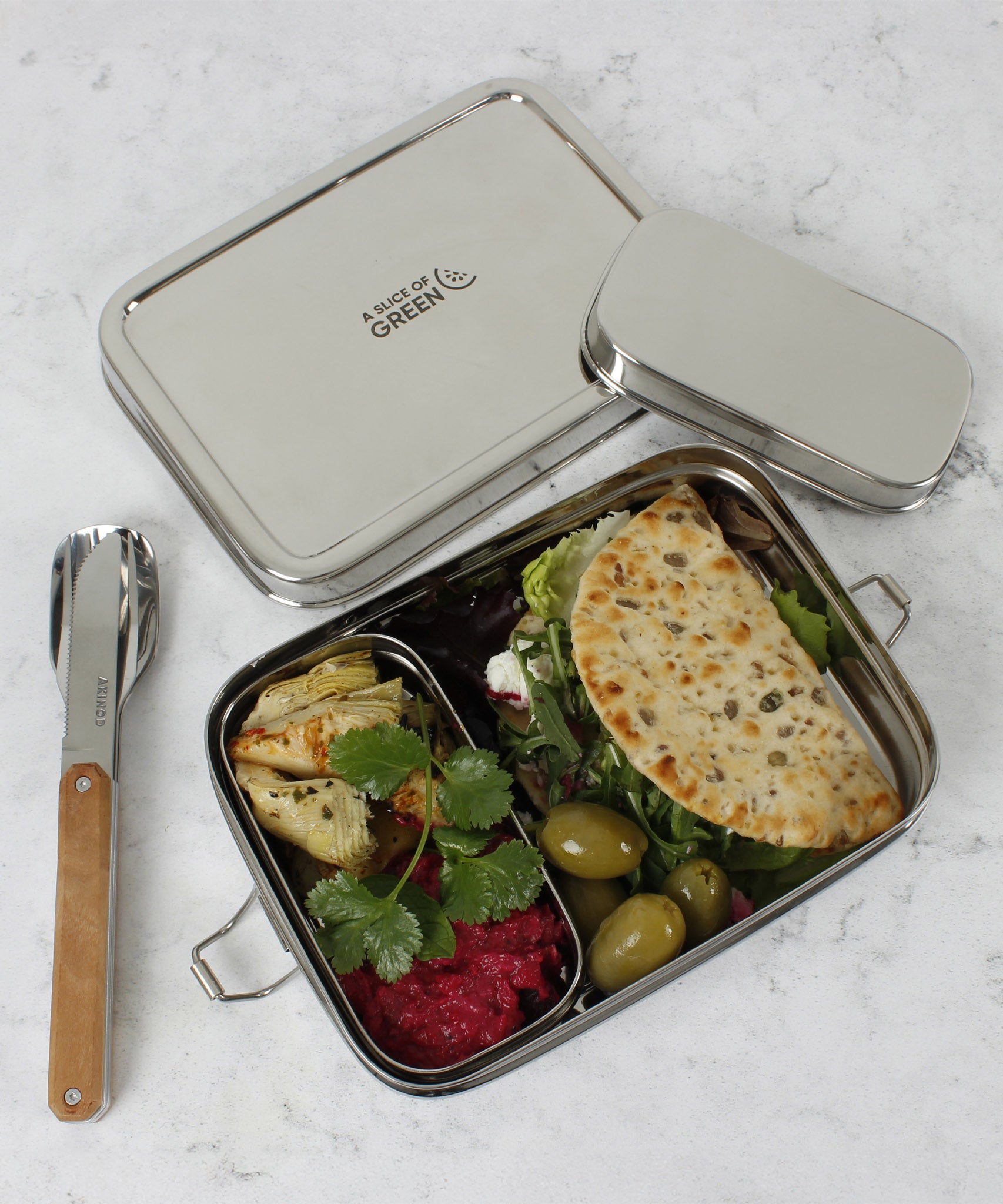 A top down image of the A slice of green large lunchbox with mini container with various food items inside