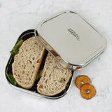 A top down image of A slice of green shimla large square container lunchbox with the lid resting on top showing the stainless steel finish detail
