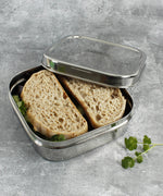 A close up of a sandwich lunch inside the A slice of green shimla large square container lunchbox