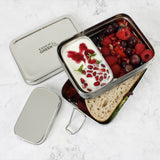 A top down image of A slice of green two tier lunchbox with mini container stacked on top of eachother and showing various ruit items inside each compartment