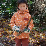 Boy playing in a forest, wearing a hooded Little Green Radicals Waterproof Winter School Coat, made from recycled bottles, with a yellow gold duck print, for sale at Babipur.