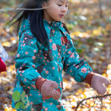 Child playing in a forest wearing a Kids Warm Waterproof Winter School Coat in Winter Rabbits print, blue and floral, by Little Green Radicals, made from recycled bottles and a cosy polyester fleece, buy now at Babipur.