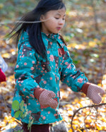 Child playing in a forest wearing a Kids Warm Waterproof Winter School Coat in Winter Rabbits print, blue and floral, by Little Green Radicals, made from recycled bottles and a cosy polyester fleece, buy now at Babipur.