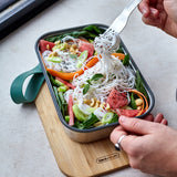 A close up of adult using the fork from the Black + Blum stainless steel cutlery set and eating from the ocean original lunchbox