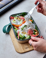 A close up of adult using the fork from the Black + Blum stainless steel cutlery set and eating from the ocean original lunchbox