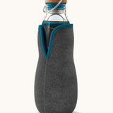 Black + Blum glass bottle with active charcoal water filter and locking coil available at Babipur. Features a felted holder with dark blue trim and a cork lid with a loop handle