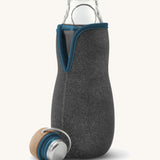 A close up of the Black + Blum glass bottle with active charcoal water filter and locking coil showing the felted holder and lid detail