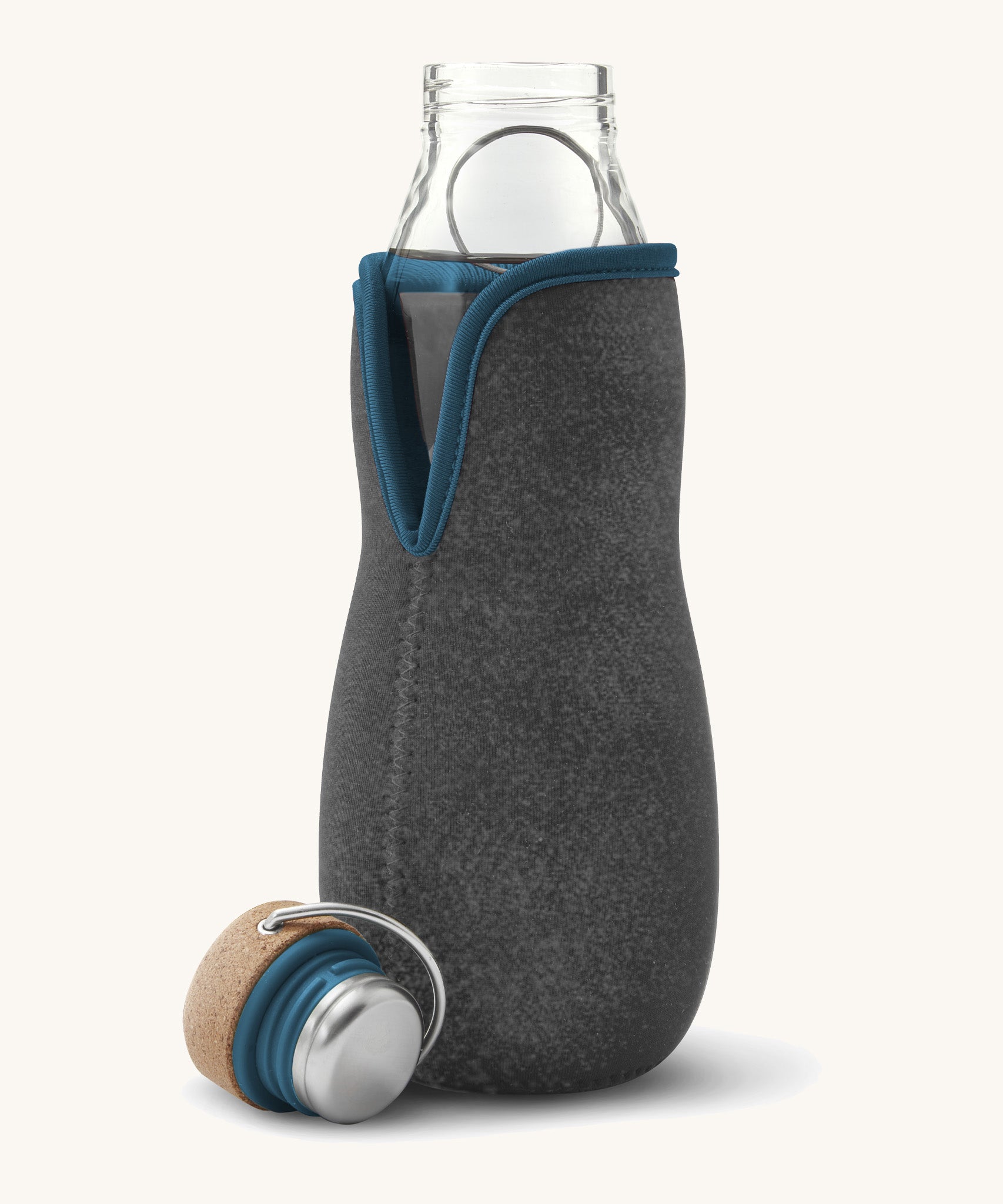 A close up of the Black + Blum glass bottle with active charcoal water filter and locking coil showing the felted holder and lid detail