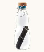 A close up of the Black + Blum glass bottle with active charcoal water filter and locking coil showing the charcoal filter detail