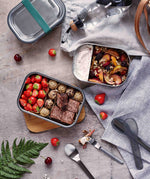 A top down view of the different Black + Blum leakproof stainless steel lunchboxes with food inside