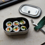 A close up of the Black + Blum leakproof stainless steel lunchbox with a olive silicone showing the size of the box with food inside