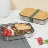A sandwich and tomatoes inside a Black + Blum stainless steel airtight stainless steel sandwich box with a olive silicone holder available at Babipur.