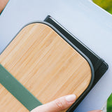 A close up of a sandwich in a Black + Blum stainless steel airtight sandwich box showing the bamboo lid detail