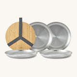 A close up of the Black + Blum set of 4 stainless steel plates showing the protective bamboo lid and plate detail