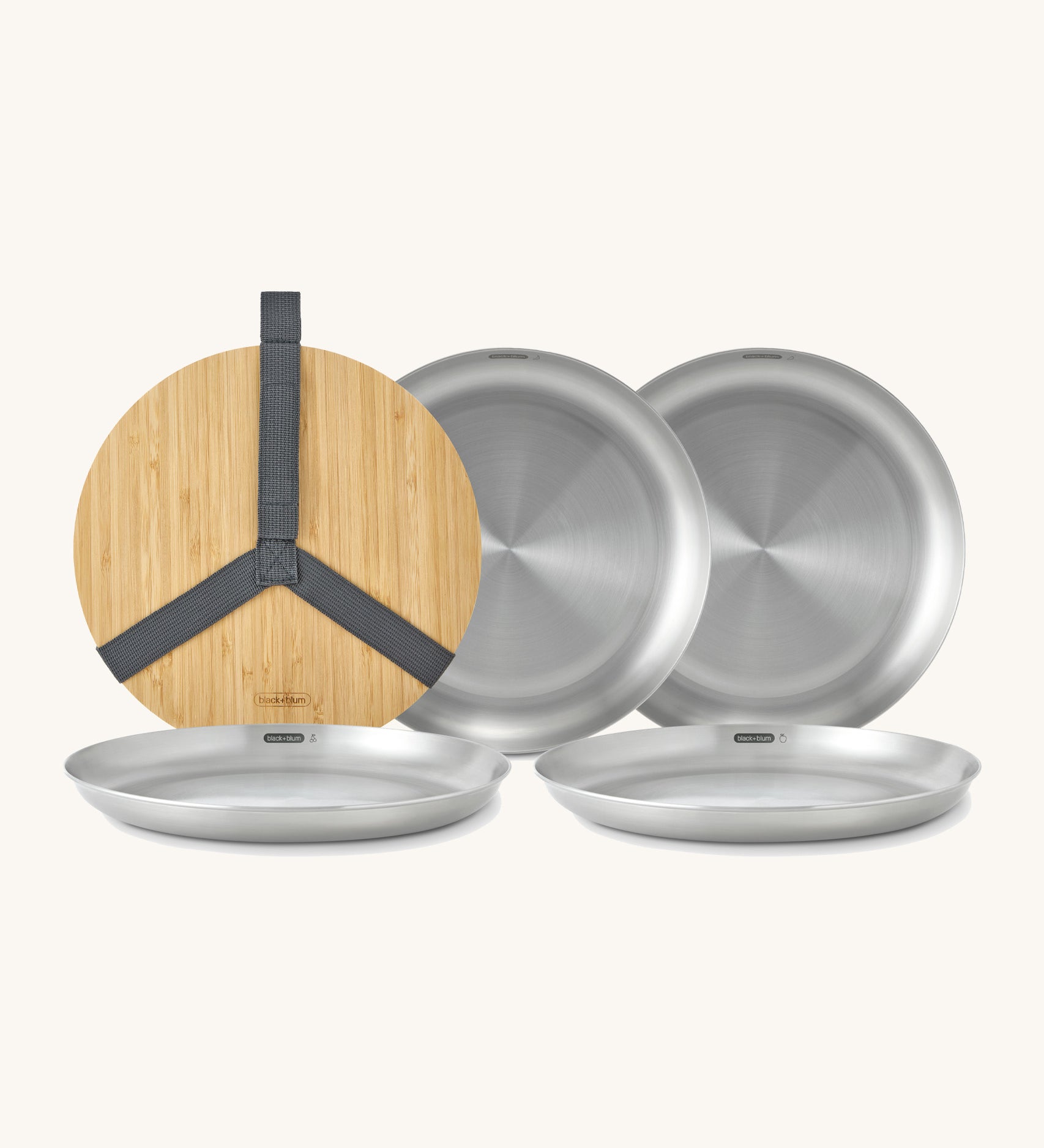 A close up of the Black + Blum set of 4 stainless steel plates showing the protective bamboo lid and plate detail