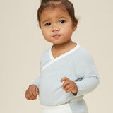 A toddler wearing the Mori organic cotton and bamboo kimono bodysuit in a blue stripe design, with some blue stripe joggers.