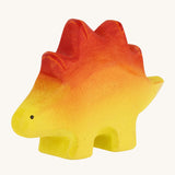 Bumbo wooden baby stegosaurus toy figure on a plain background