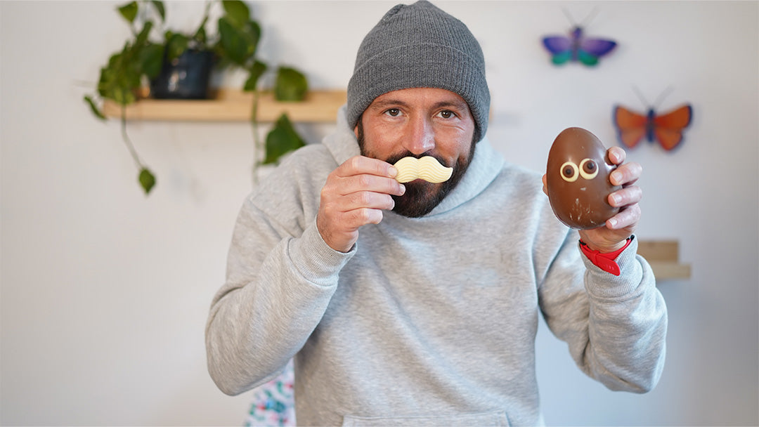 Man holding a Cocoa Loco fairtrade chocolate easter egg, holding the white chocolate moustache to his mouth