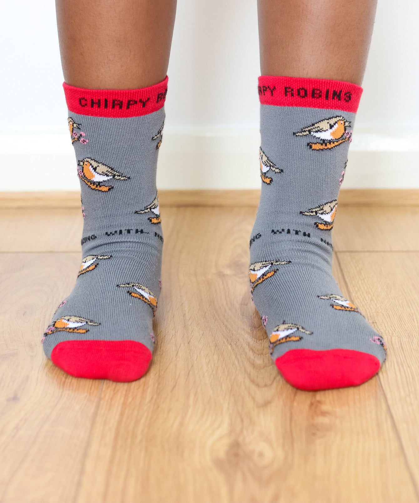 A close up of a child wearing the Eco kiddies organic cotton chirpy robbins socks showing the cute robin design and red trim detail