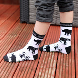 A close up of a child wearing the Eco kiddies organic cotton wild about wildlife socks showing the cute panda, elephant and rhino design with black trim detail