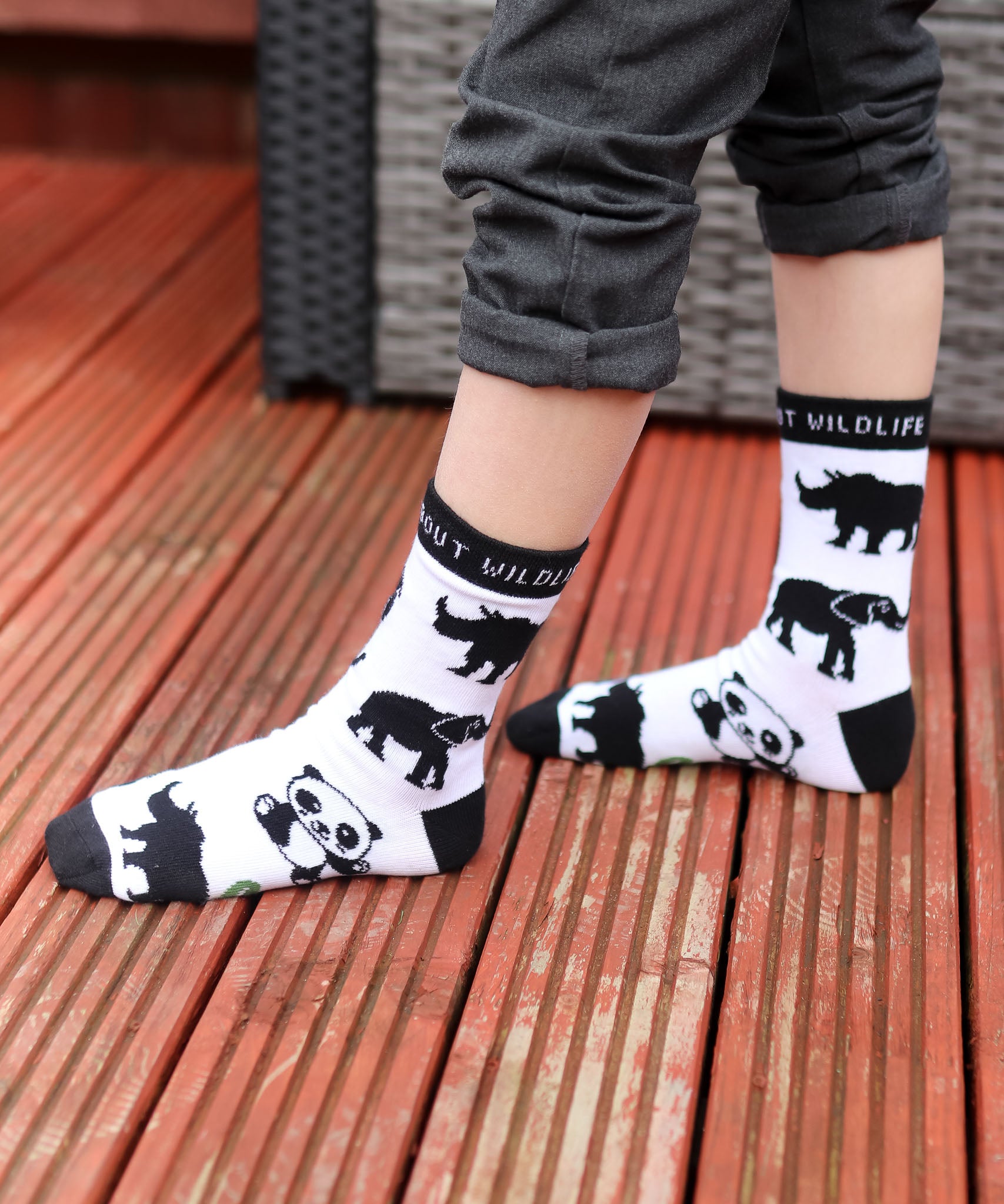 A close up of a child wearing the Eco kiddies organic cotton wild about wildlife socks showing the cute panda, elephant and rhino design with black trim detail