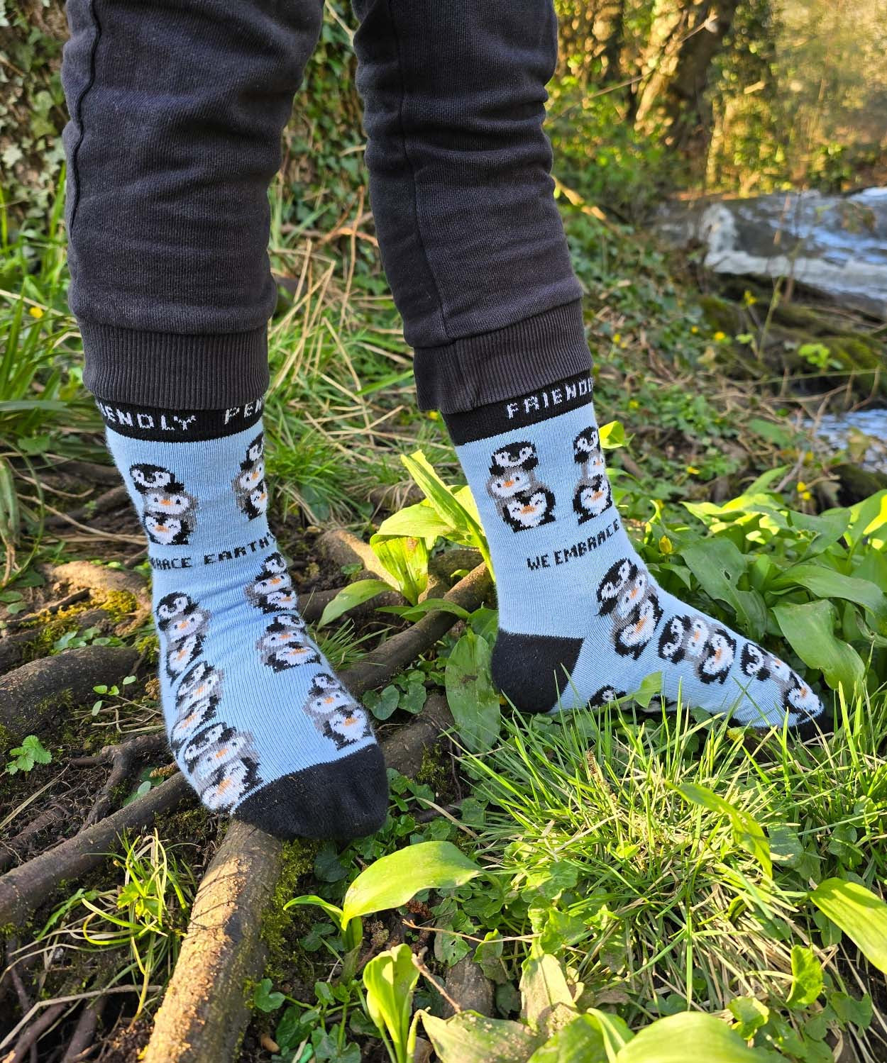 A child standing on branches and wearing the Eco kiddies organic cotton friendly penguins light blue socks