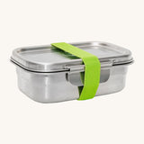 A green strap holding the Elephant Box Clip & Seal Lunchbox With Removable Divider - 800ml box and lid on a cream background