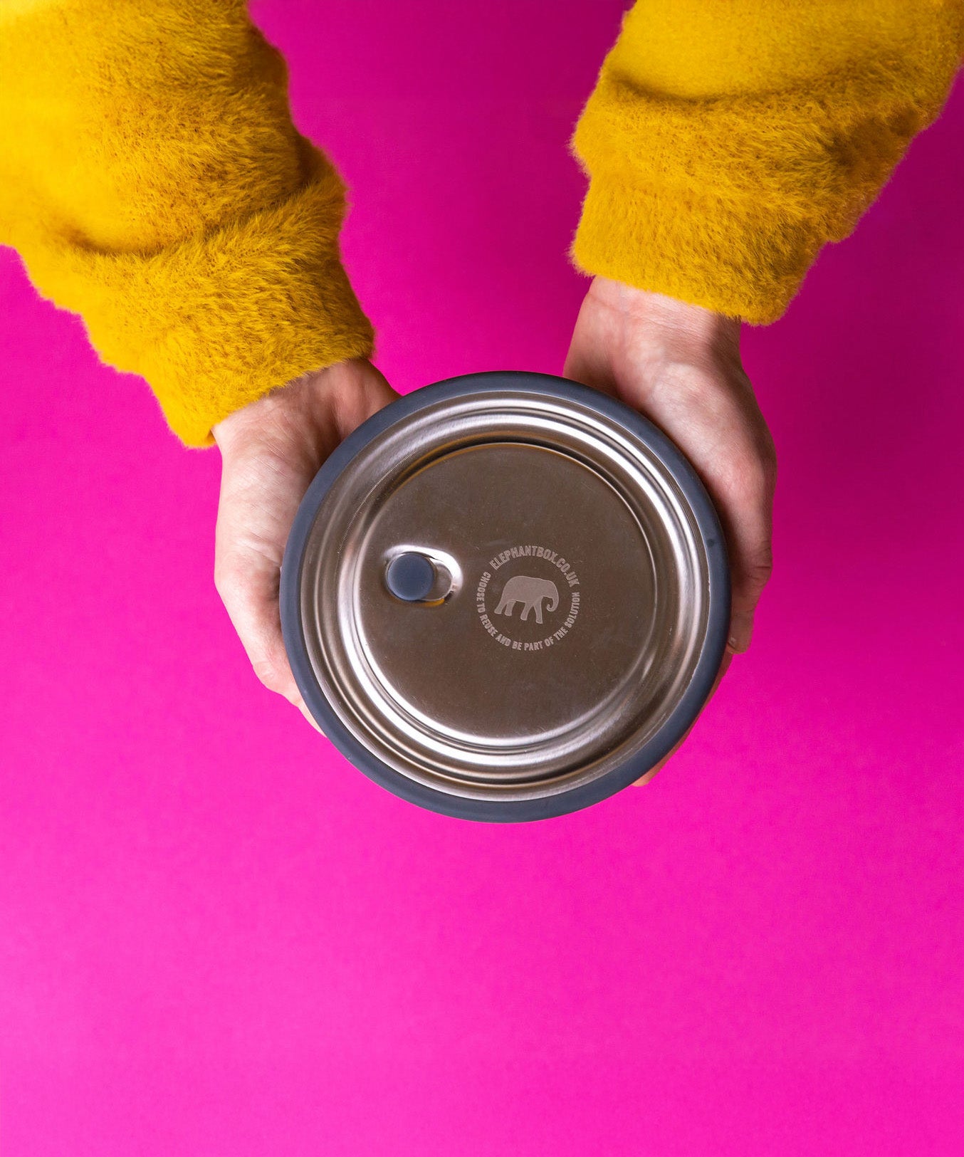 An adult hand holding the Elephant box medium lunchbowl against a bright pink background. Lunchbowl available at Babipur.