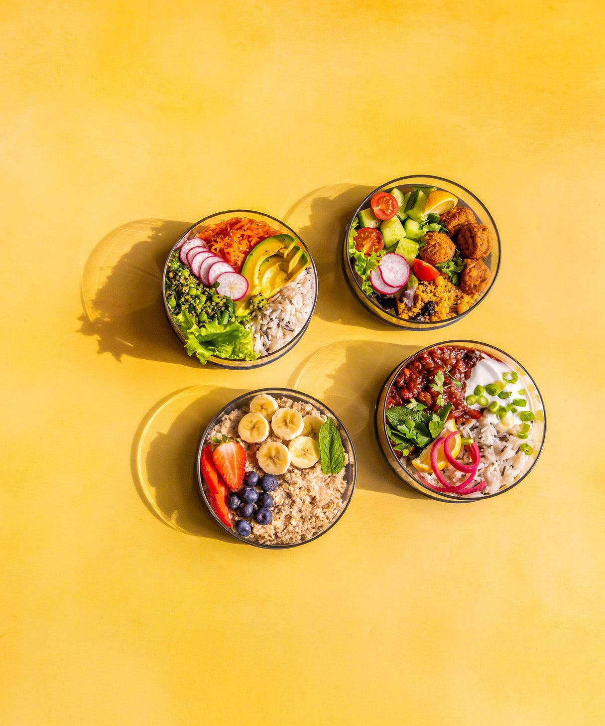 A top down image of the different Elephant box lunch bowls with the lids off and full of different healthy foods.