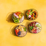 A top down image of the different Elephant box lunch bowls with the lids off and full of different healthy foods.