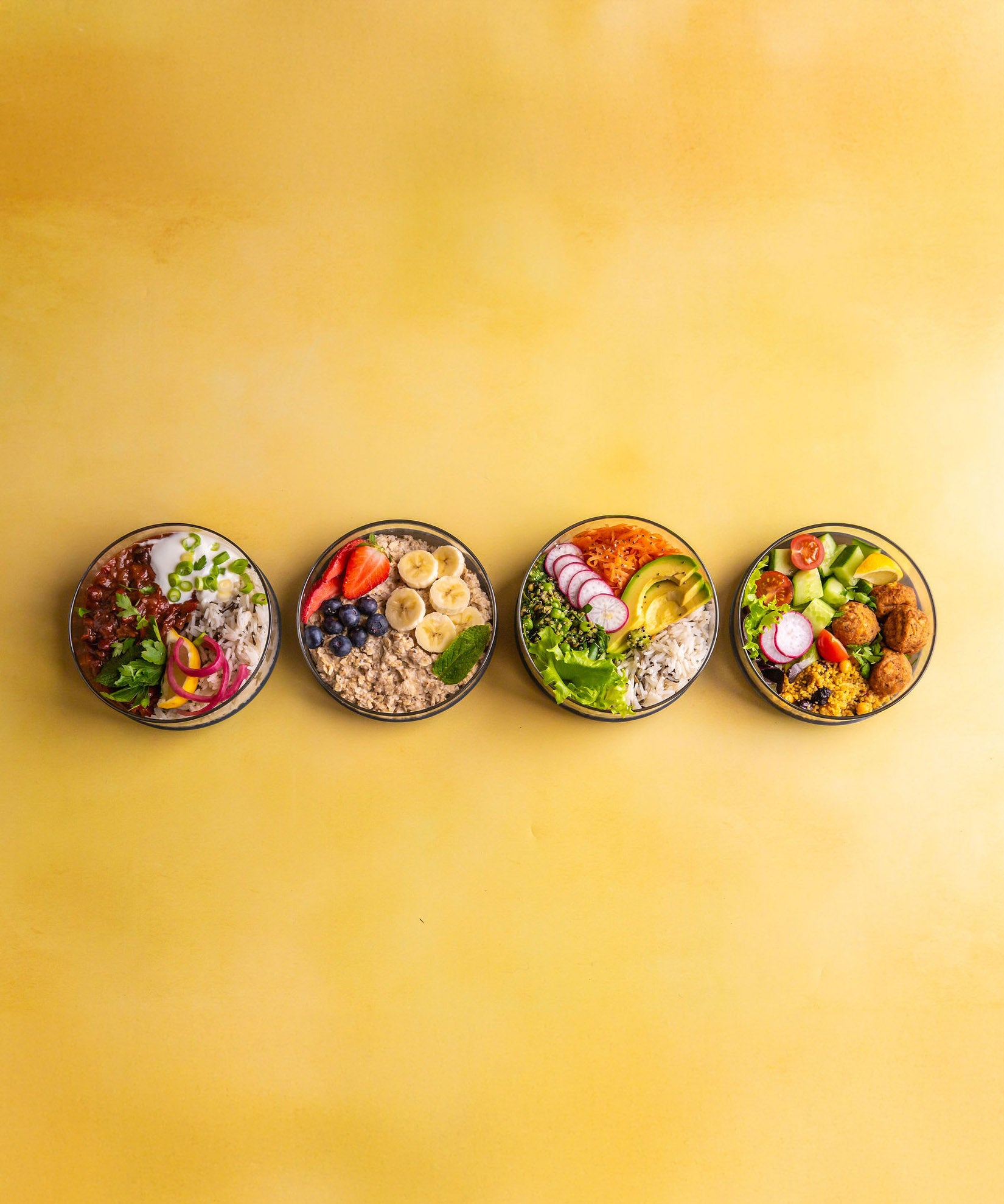 A row of Elephant Box lunch bowls available at Babipur. Bowls are without their lids and showing each bowl full of different foods.