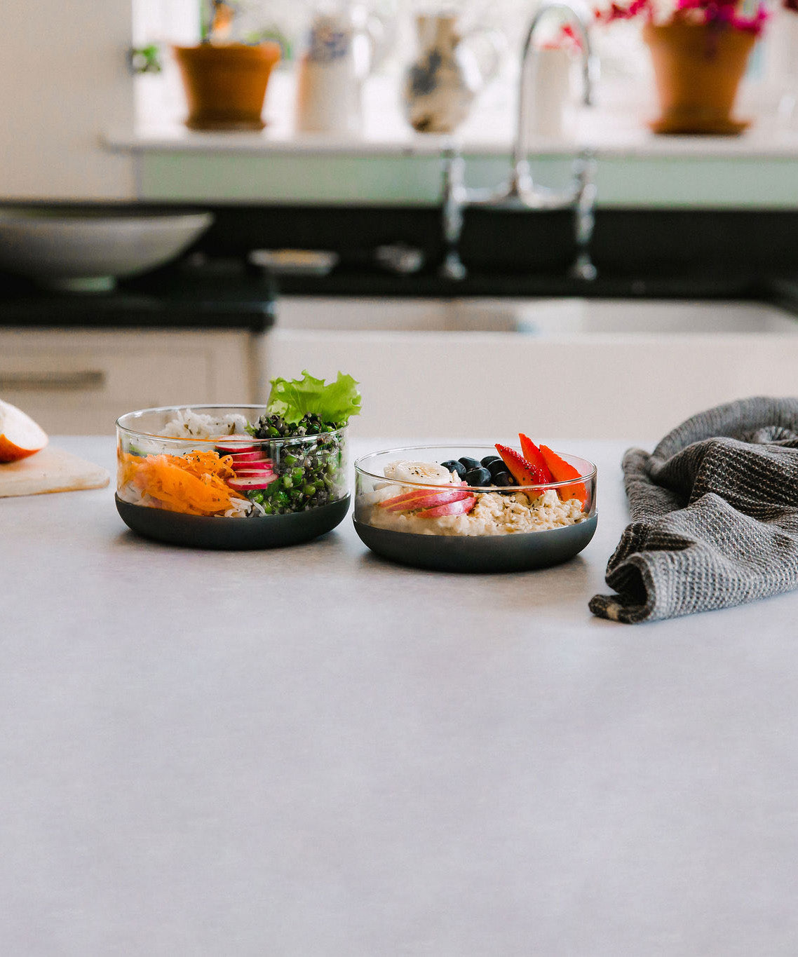 The large and medium Elephant box lunch bowls on a kitchen counter with the lids off and full of different healthy foods. Both bowls are available at Babipur.