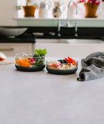 The large and medium Elephant box lunch bowls on a kitchen counter with the lids off and full of different healthy foods. Both bowls are available at Babipur.