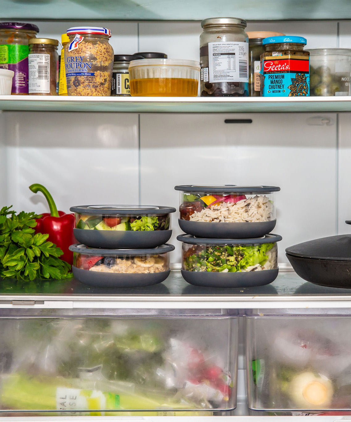 A stack of medium and large Elephant box lunch bowls in a fridge and packed with different foods. Both bowls are available at Babipur.