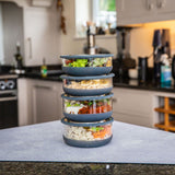 A stack of medium and large Elephant box lunch bowls on a kitchen counter and packed with different foods. Both bowls are available at Babipur.