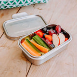 A nice selection of fruit and veg inside the Elephant Box Clip & Seal Lunchbox With Removable Divider - 800ml. The lid is laid behind the lunch box which is on a wooden background