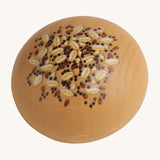 Erzi Wooden Seed Roll. A light brown wooden bread roll, with painted seeds and grains on top. On a cream background