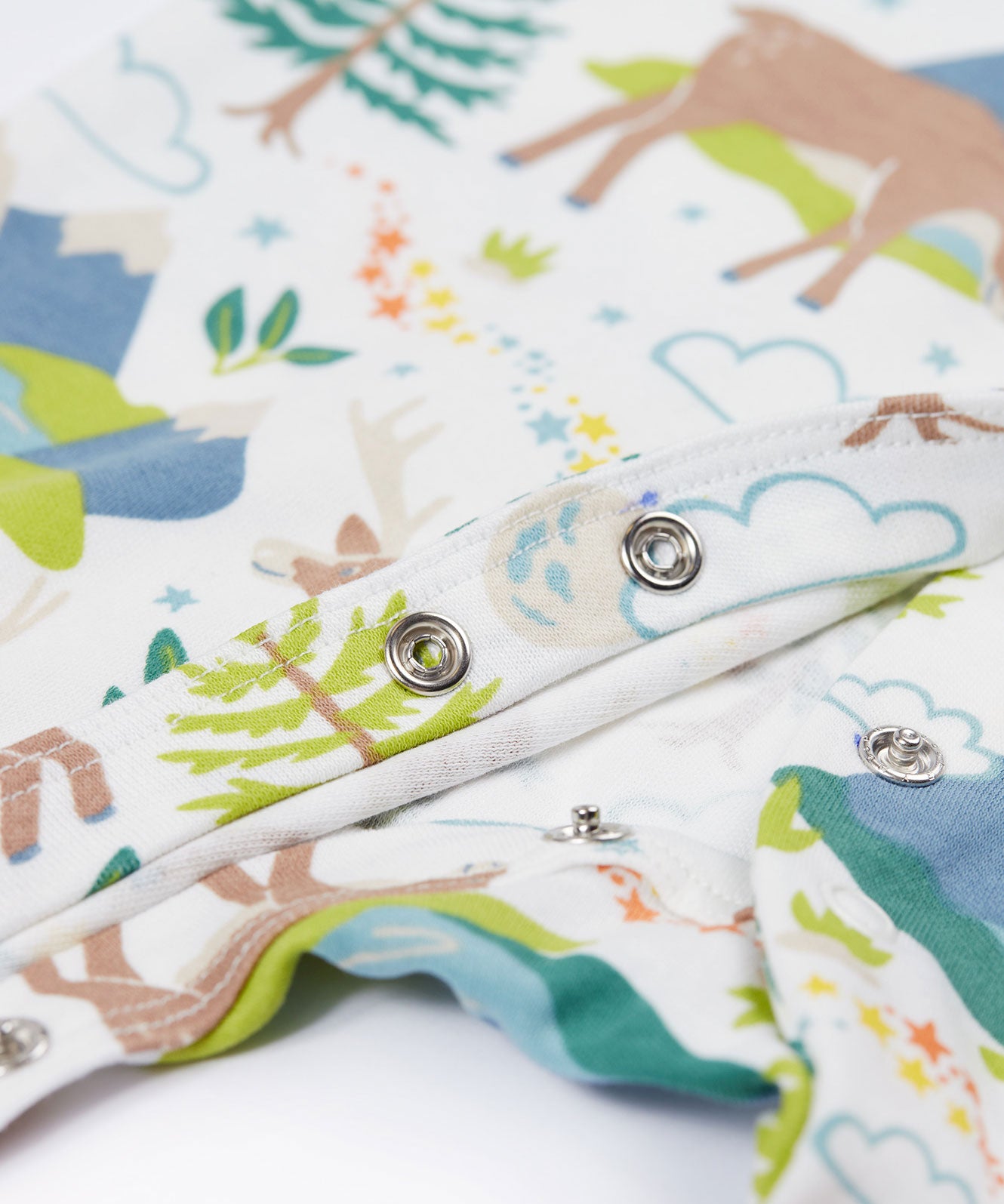 A close up of the popper closure on the A Frugi Caribou Fields Organic Cotton Lovely Babygrow. A white babygrow with a reindeer themed print with green and blue details. This babygrow is a part of a wide range of organic cotton clothing for children available here at Babipur.