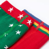 A close up of the waistbands on the Frugi Norah tights in green robin and berry red 2 pack available at Babipur. A pair of GOTS organic cotton tights in green with white stars and a robin design. Other pair is a bright festive red.