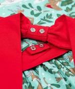 A close up of the red bow that can be poppered onto the back of the Frugi party skater dress in festive forest available at Babipur. A GOTS organic cotton dress in mint green with a playful winter / festive print. Features a red tie around the waist
