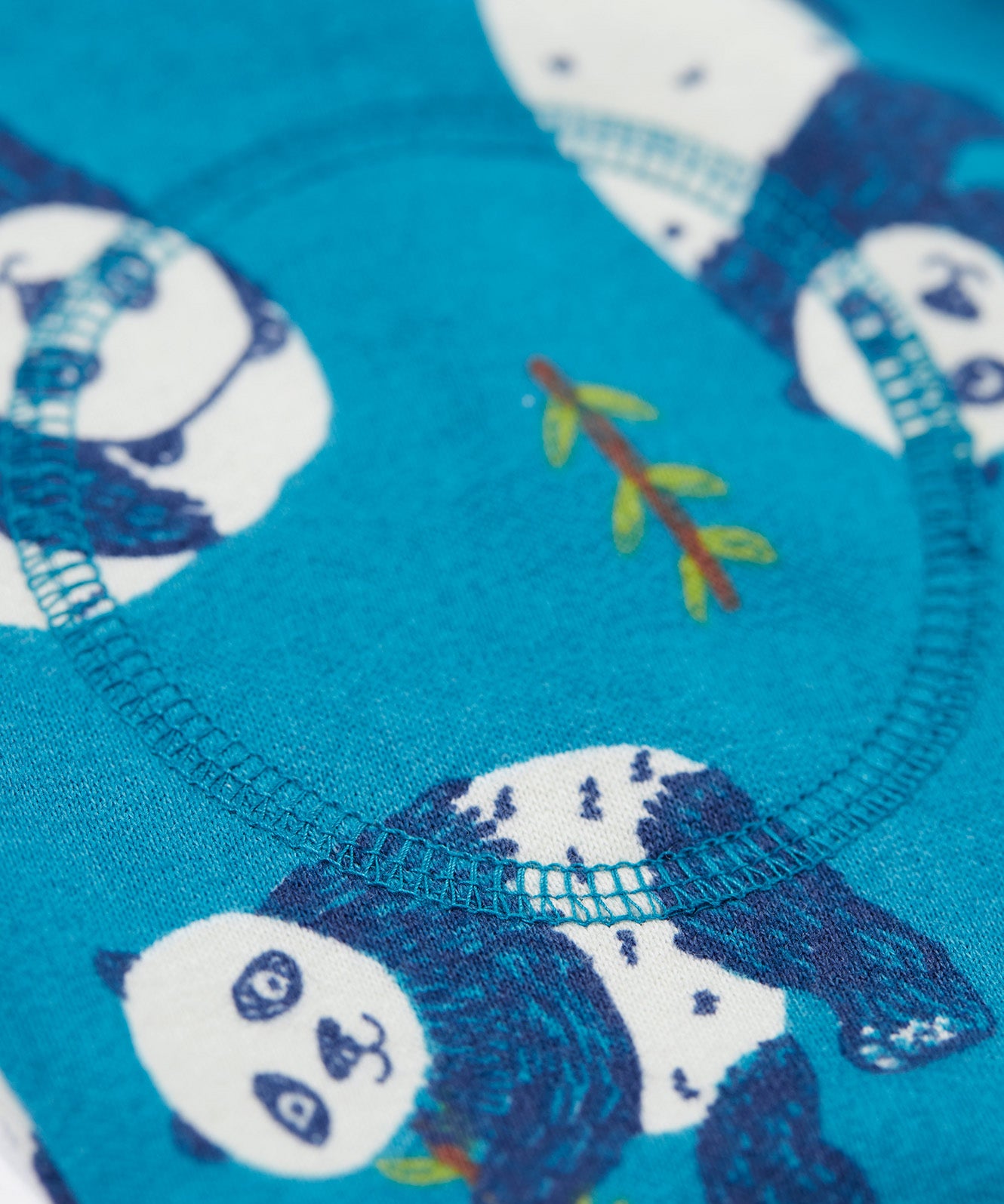 A close up of teh knee patches on the Frugi snuggle crawlers in panda pals available at Babipur. A GOTS organic cotton jooger style bottom in light blue with a playful panda print. Features soft knee patches and a yellow drawstring cord around the waist.