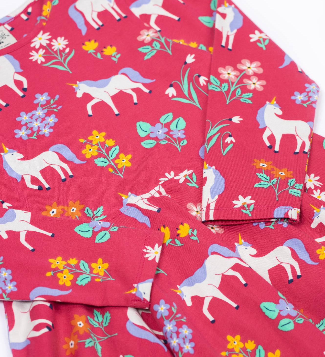 A close up of the Frugi sofia skater dress in rose / unicorn floral available at Babipur. A GOTS organic cotton dress in light pink with a cute unicorn and floral design.